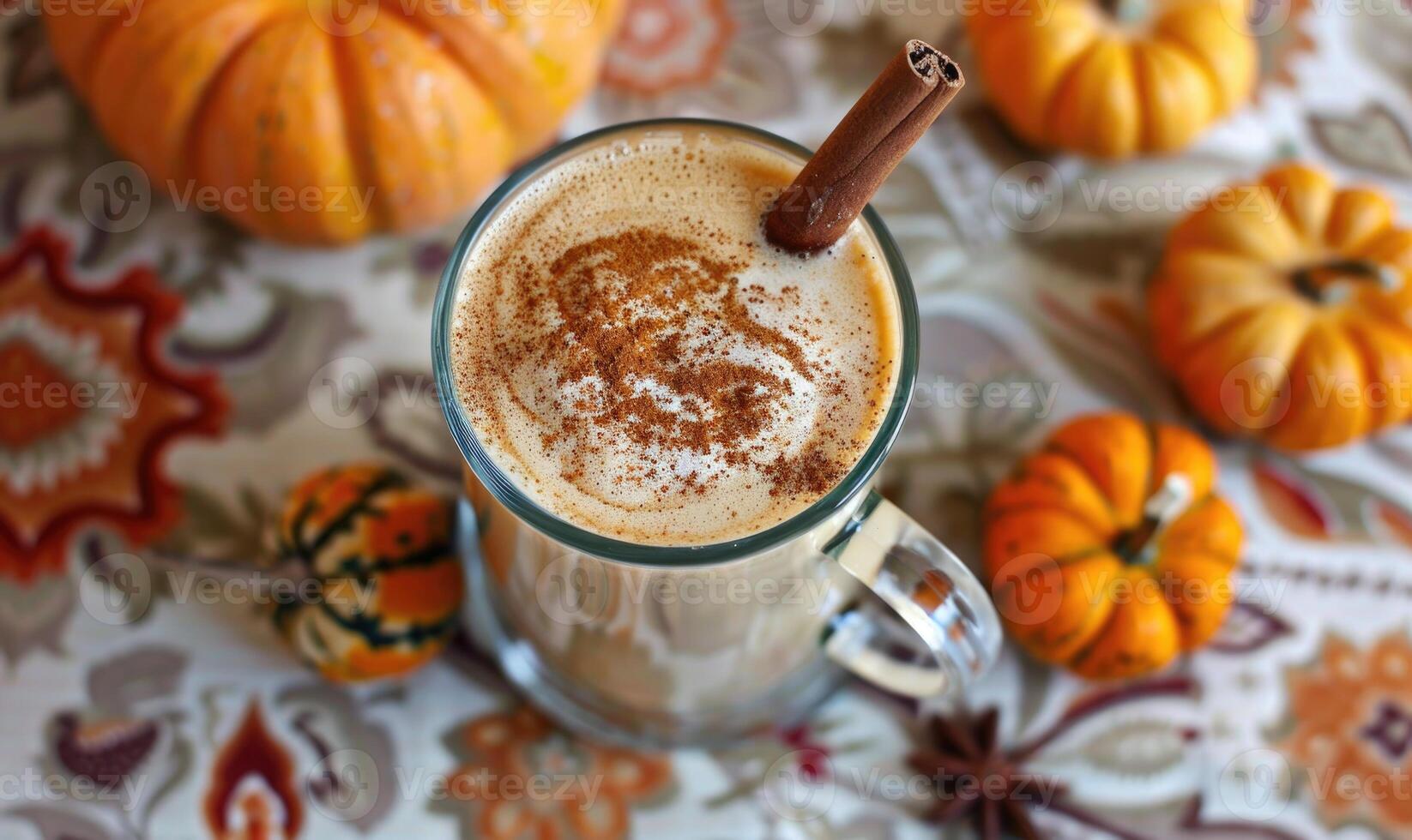 A pumpkin spice latte with a cinnamon stick and small pumpkins photo