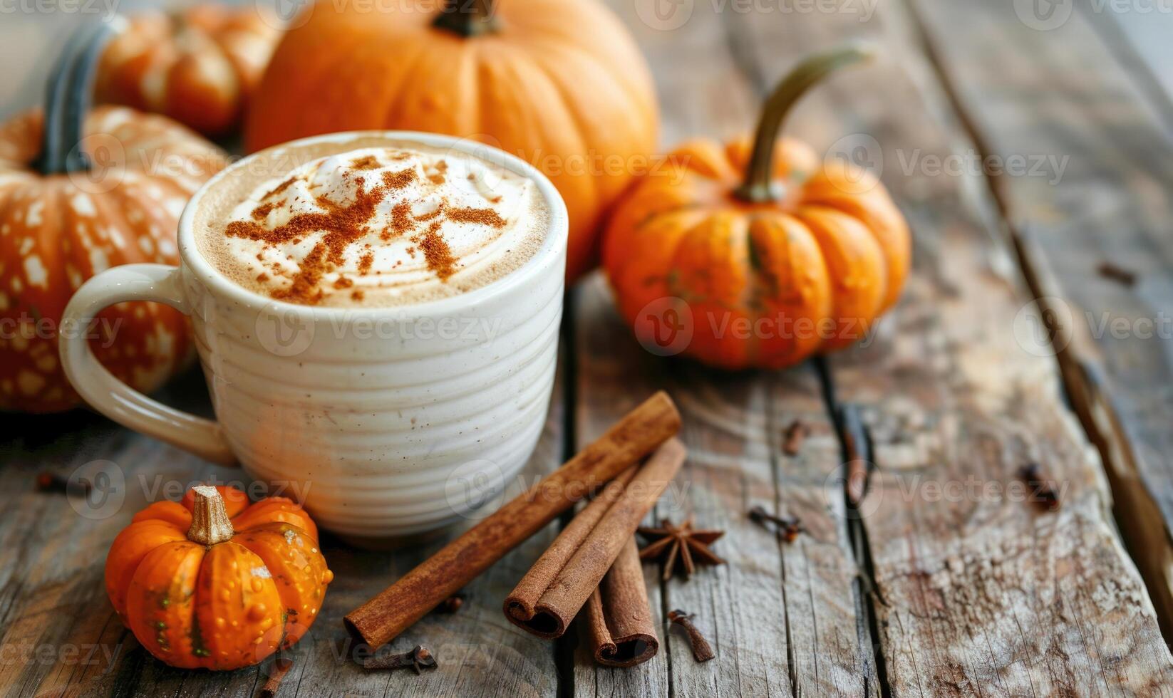 A pumpkin spice latte with a cinnamon stick and small pumpkins photo
