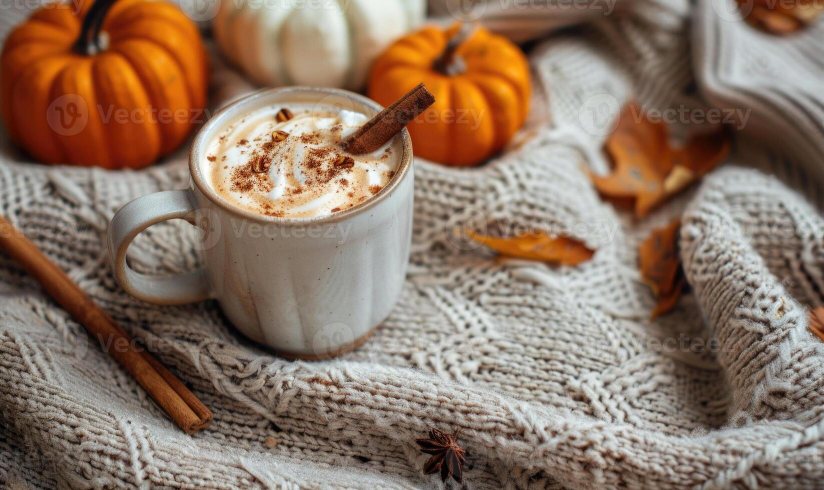 A pumpkin spice latte with a cinnamon stick and small pumpkins photo
