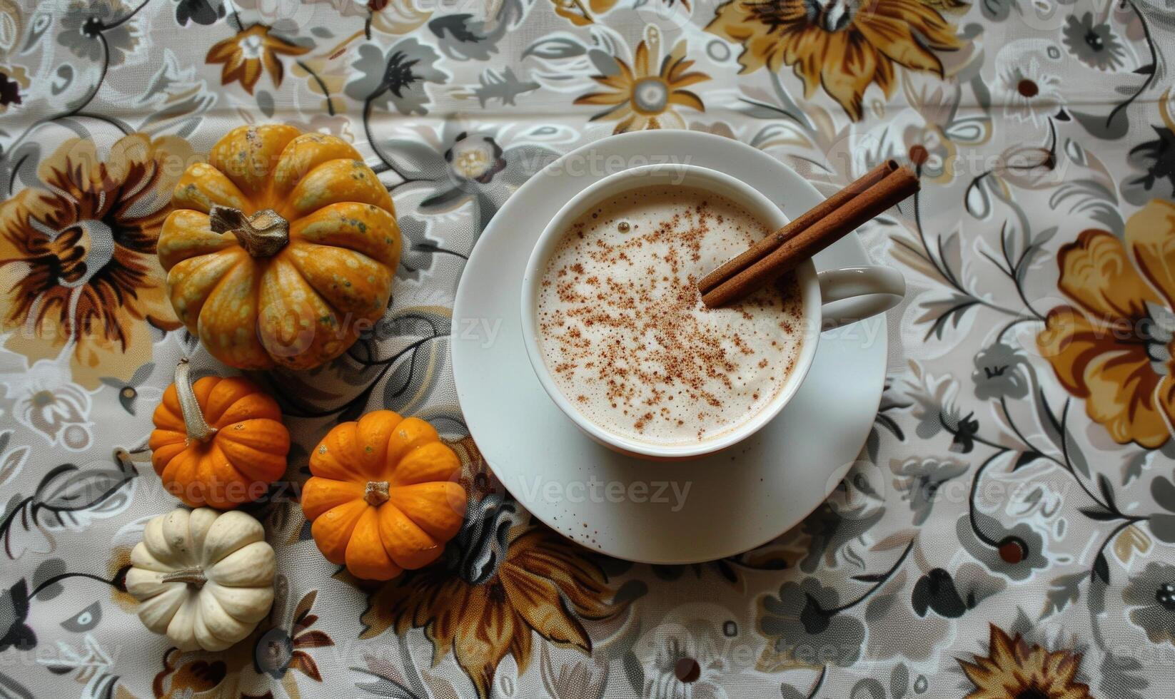 A pumpkin spice latte with a cinnamon stick and small pumpkins photo