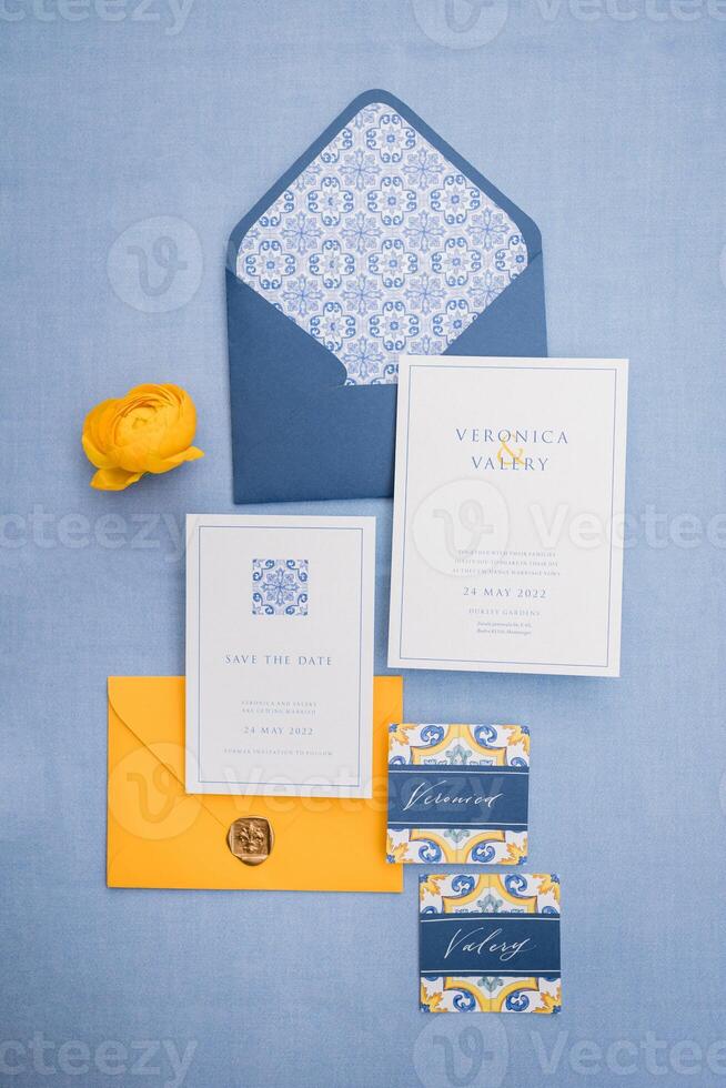 Yellow flower lies next to invitations and name cards on a blue canvas photo