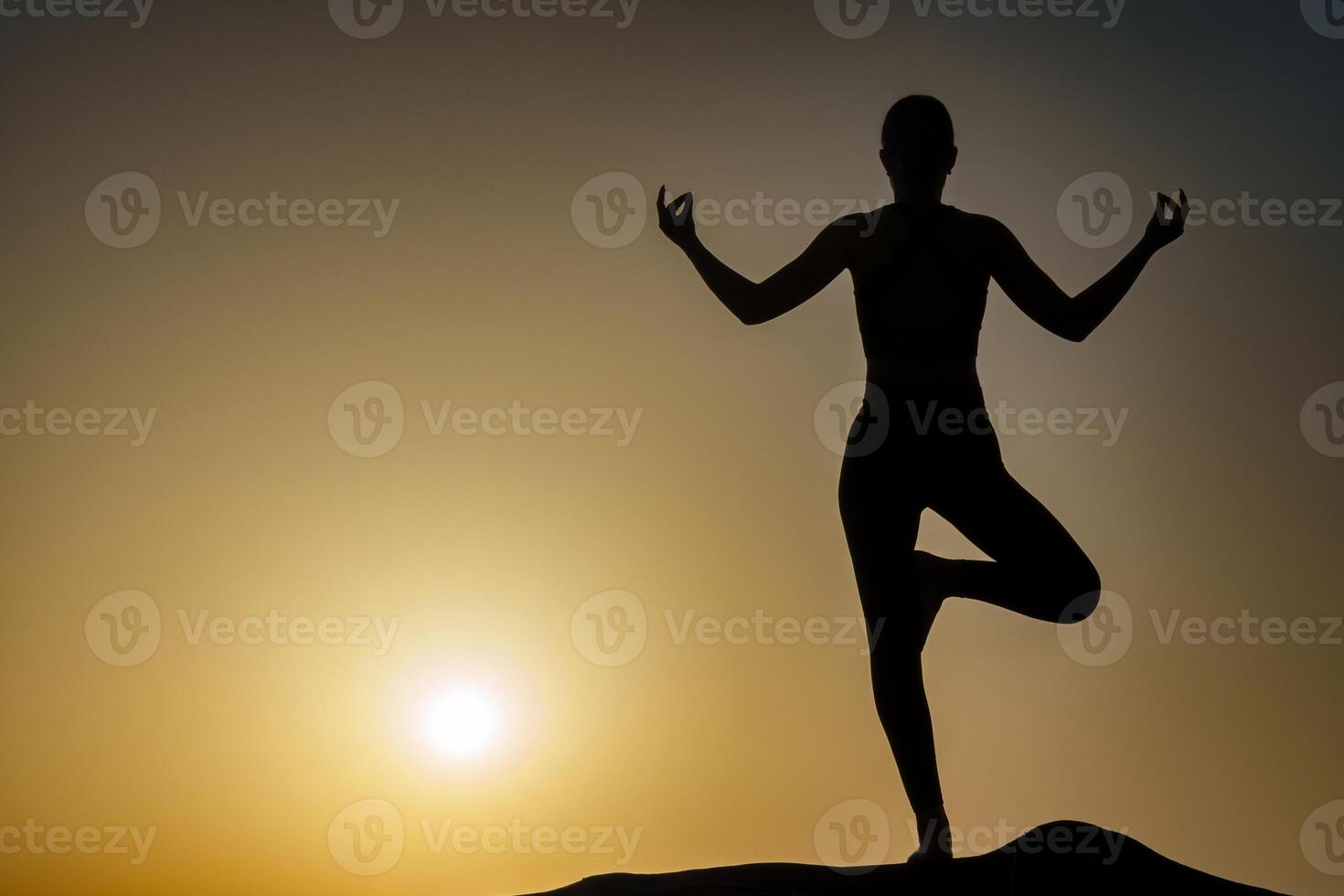 Silhouette of a girl on the background of the sunset standing on one leg, doing yoga. The concept of coaching, consulting, instructing photo