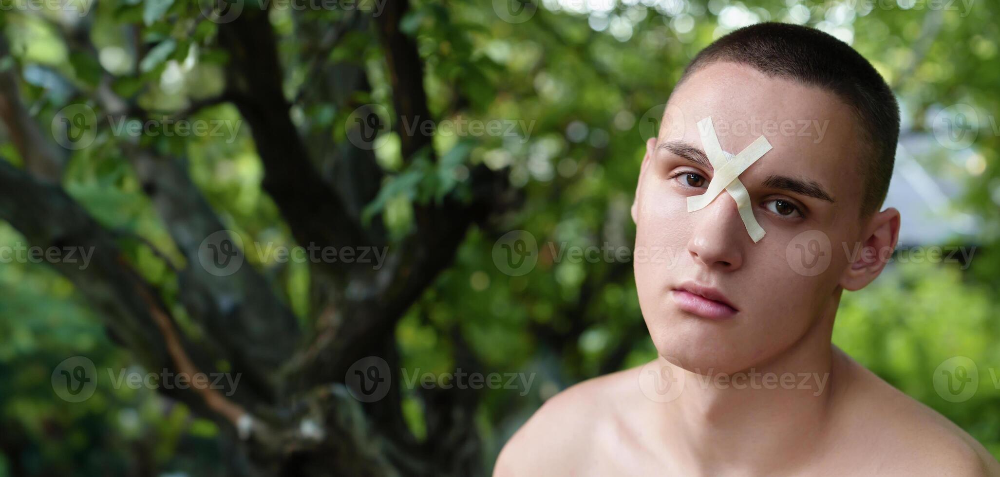 Person with a head laceration, wearing a medical bandage, in a wilderness landscape. Evokes a concept of first aid needed after an incident during outdoor pursuits photo