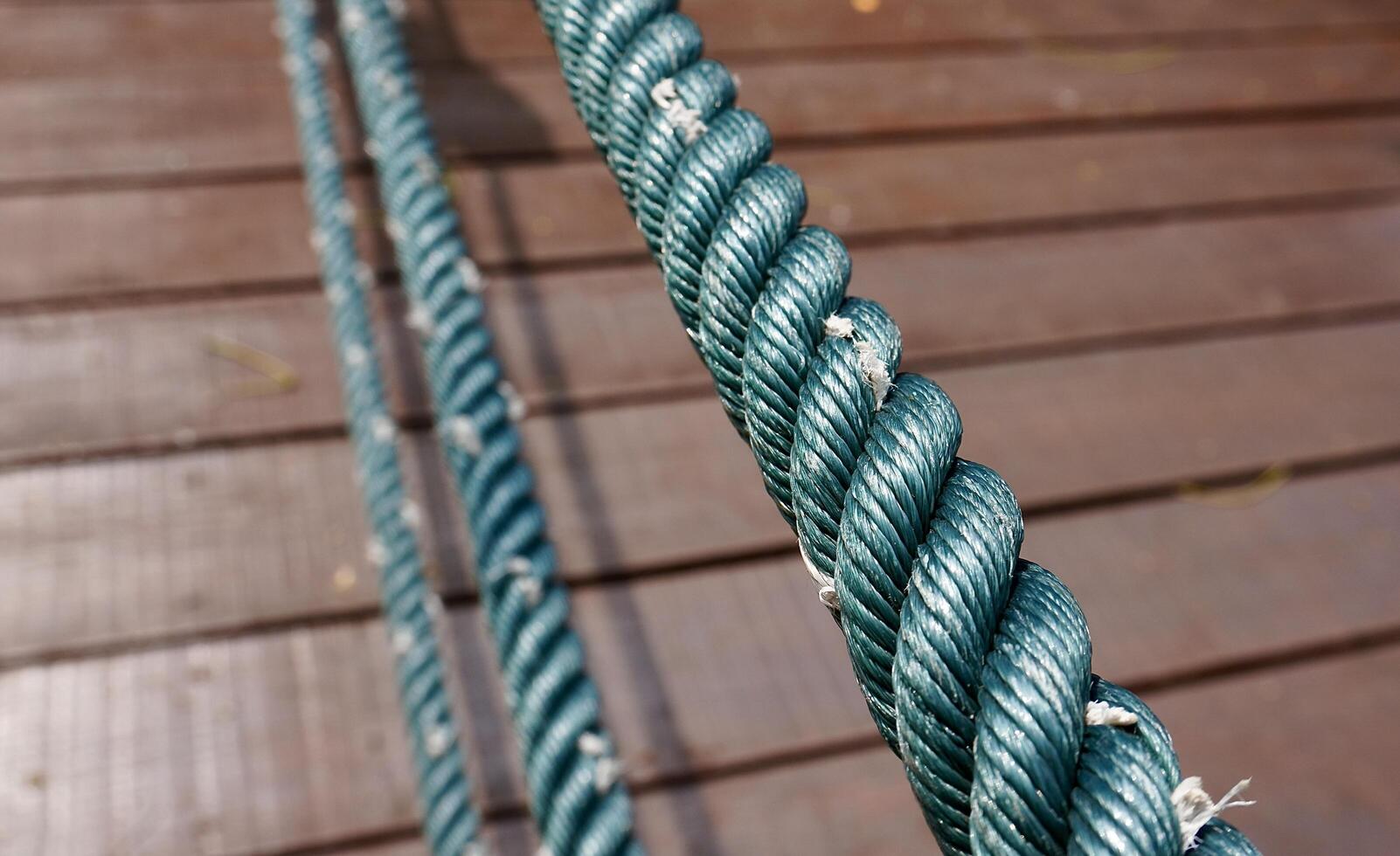 Close up thick rope texture isolated on horizontal wooden bridge flooring pavement background. photo