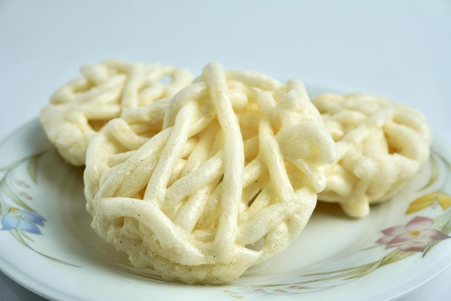 Three white kerupuk mawar putih warung crackers on white porcelain plate. Food object photography isolated on white background. photo