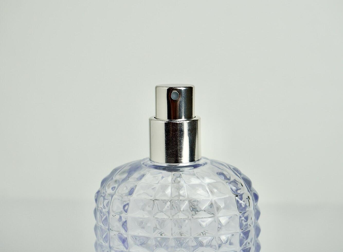 Close up textured glass perfume bottle spray with no lid on. Object photography isolated on horizontal white background. photo