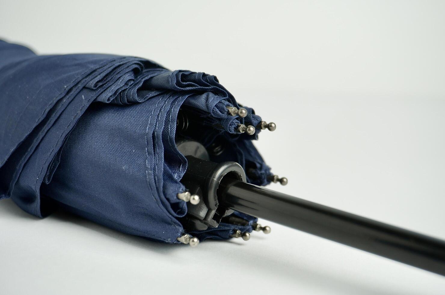 Close up part of dark blue foldable small umbrella object photography isolated on horizontal white background. photo