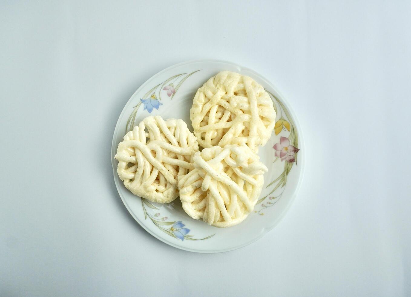 Three kerupuk putih warung crackers on white porcelain plate from above top angle view. Food object photography isolated on white background. photo