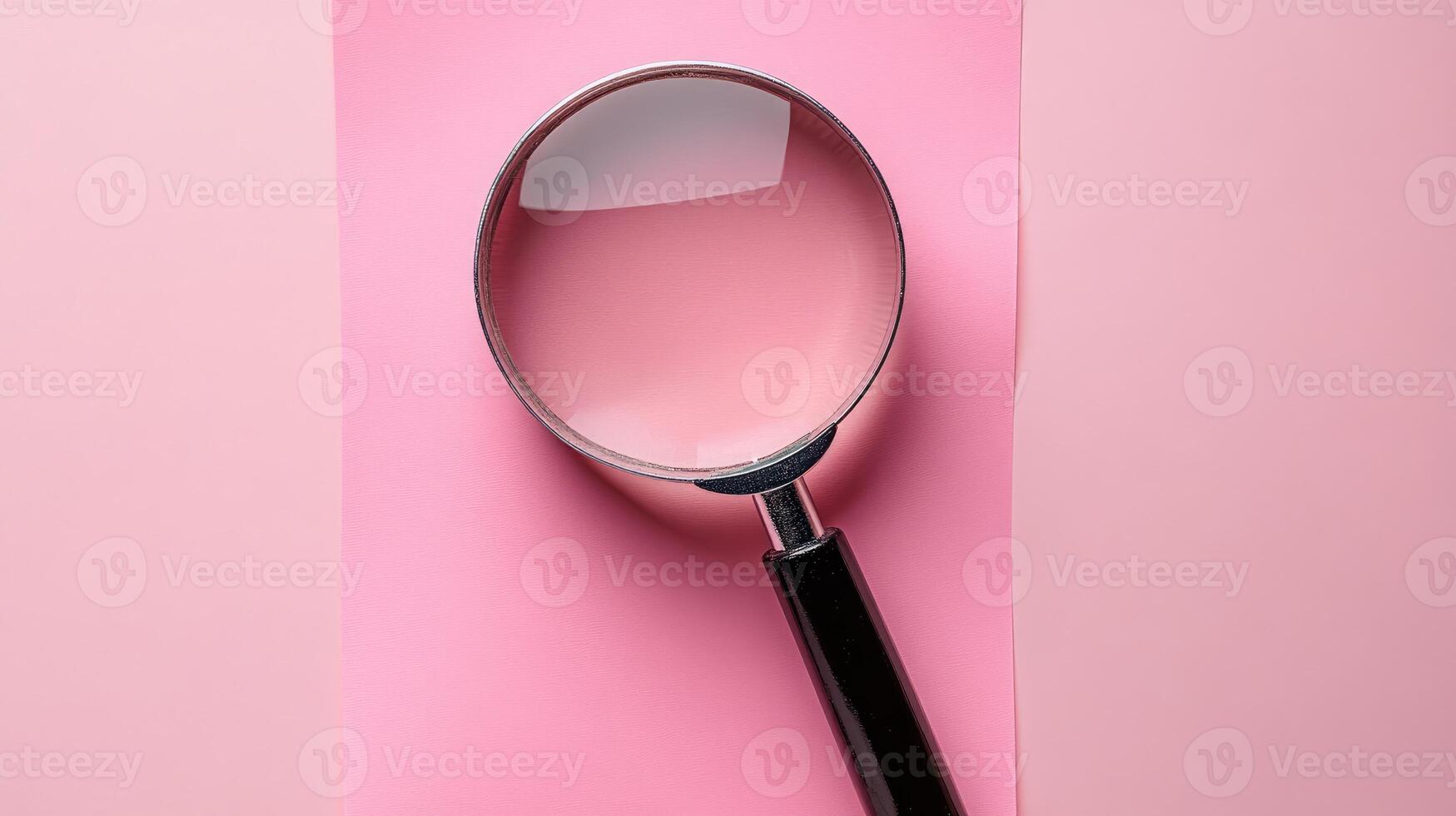 Magnifying glass resting on pink background with copy space photo