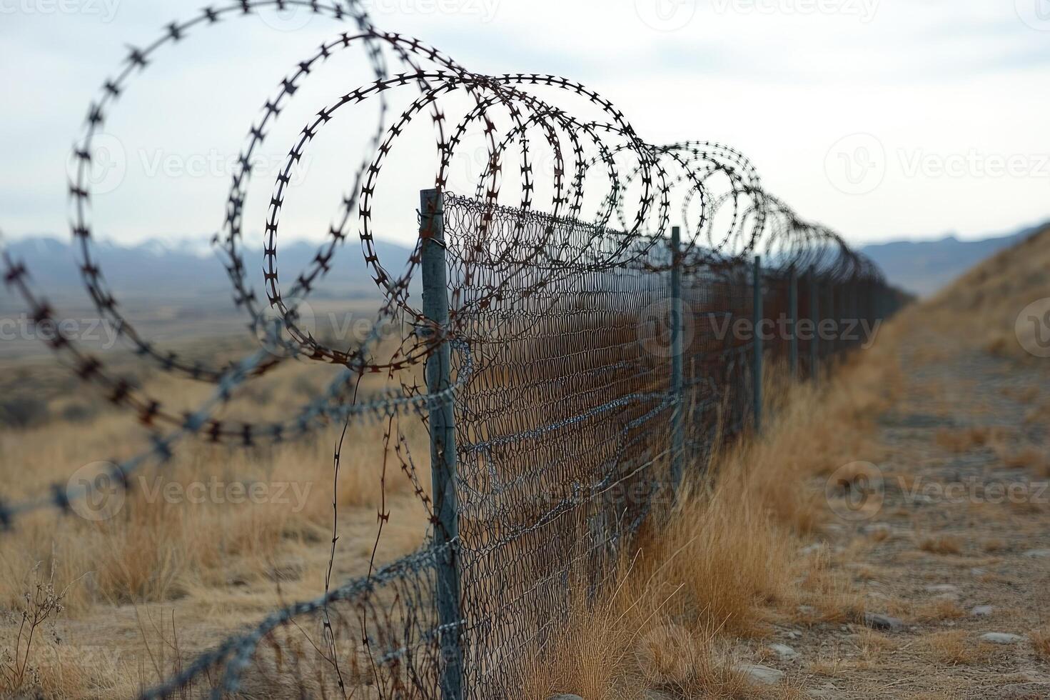 Barbed wire fence creating a secure border line under blue sky photo