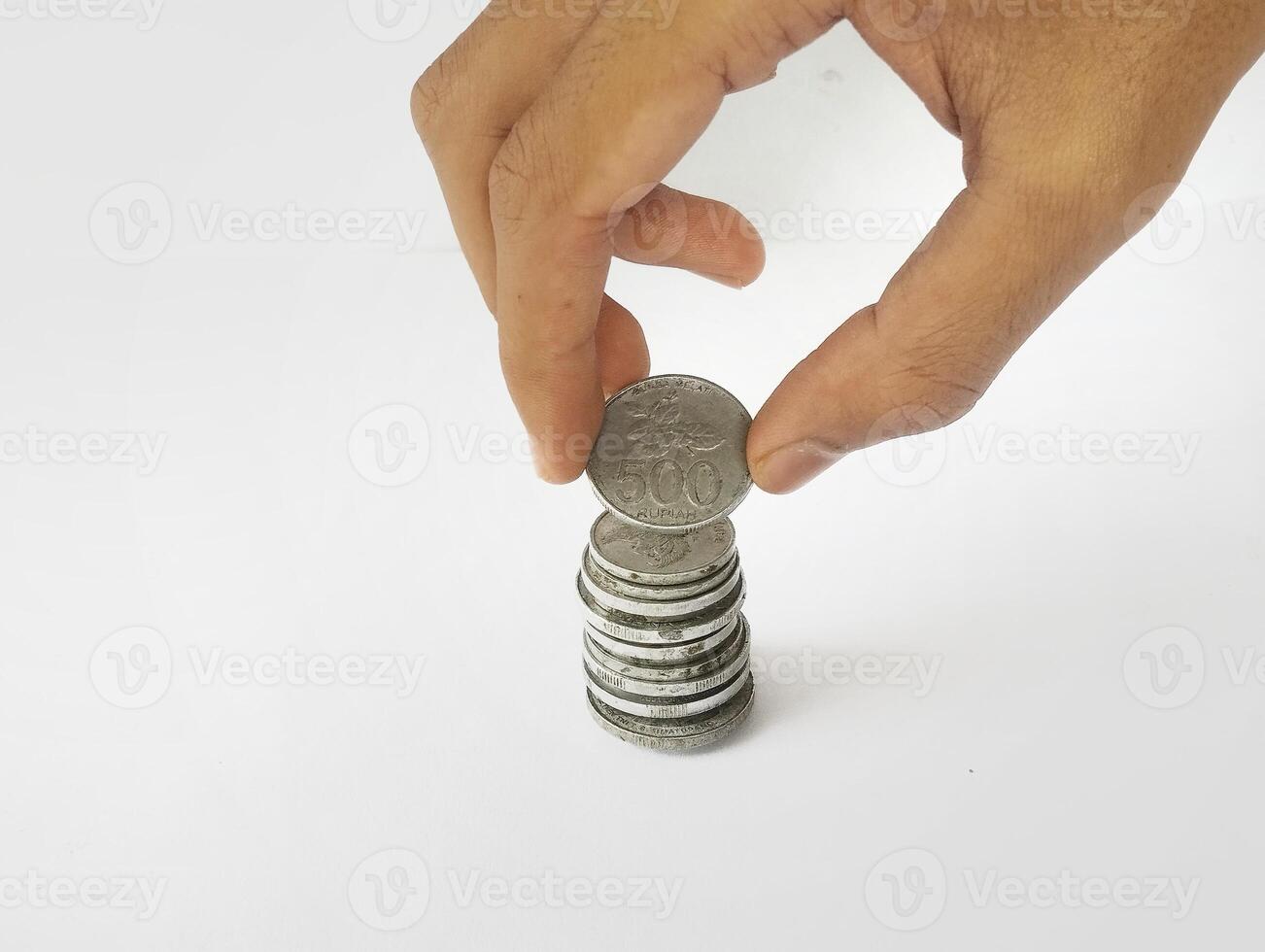 The hand is stacking Indonesian rupiah coins, isolated with a white background. photo