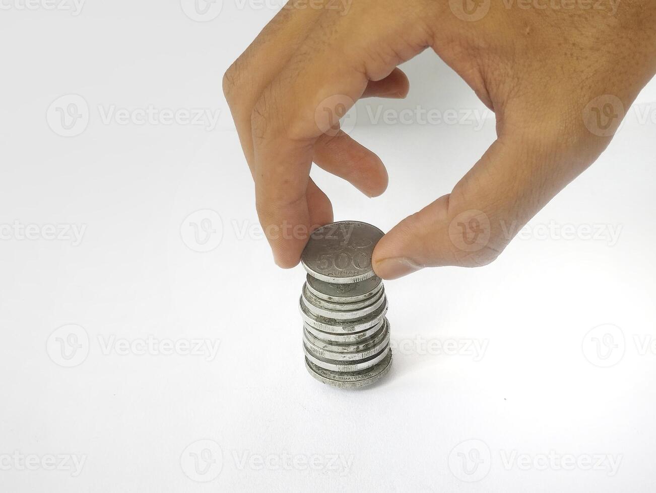 The hand is stacking Indonesian rupiah coins, isolated with a white background. photo