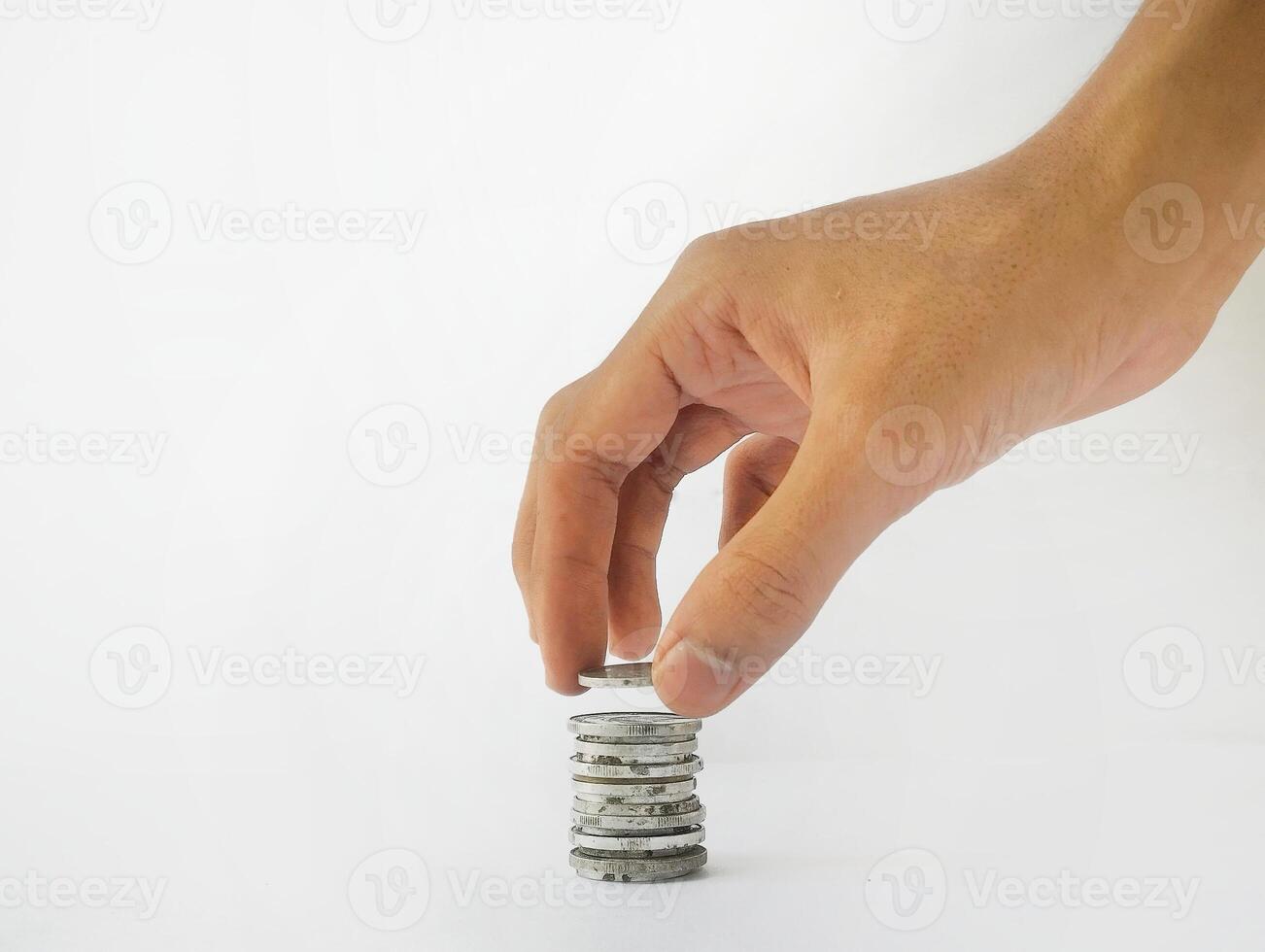 The hand is stacking Indonesian rupiah coins, isolated with a white background. photo