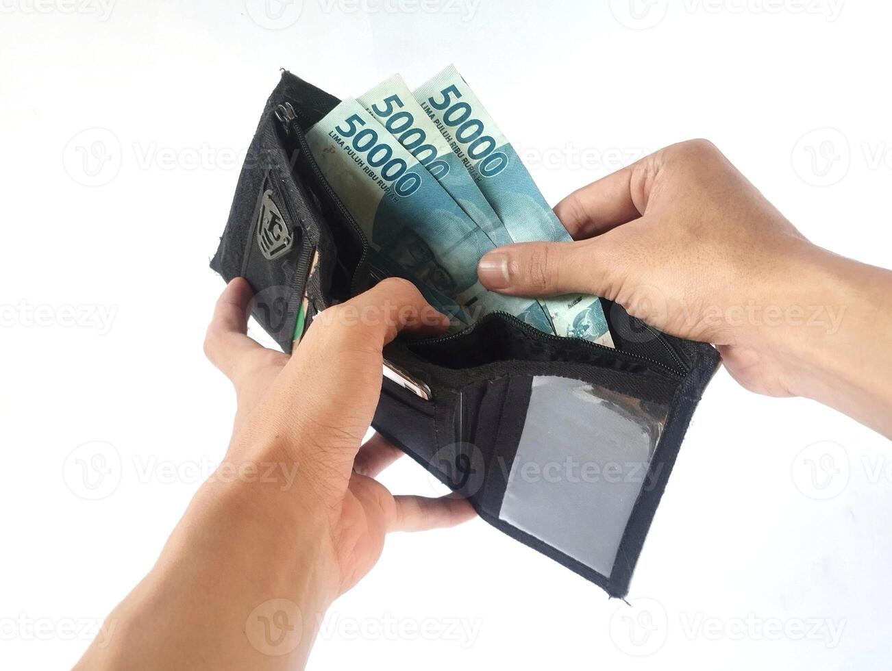 A man's hand takes and shows money from a wallet isolated on white background, rupiah is the currency of Indonesia photo