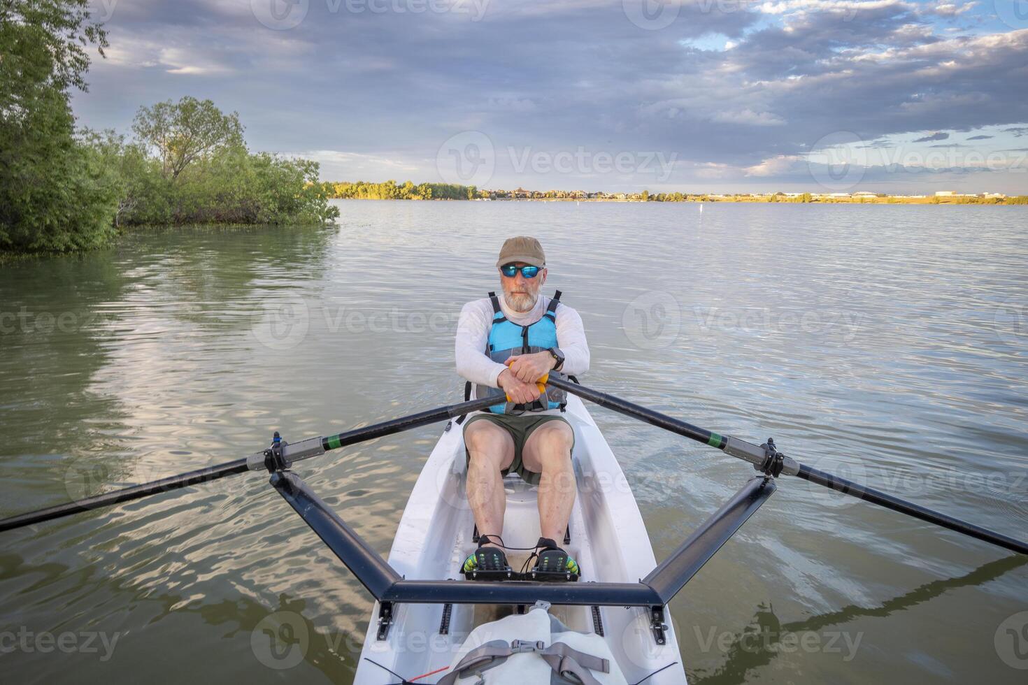 senior man in a rowing shell on a calm lake in Colorado in summer scenery photo