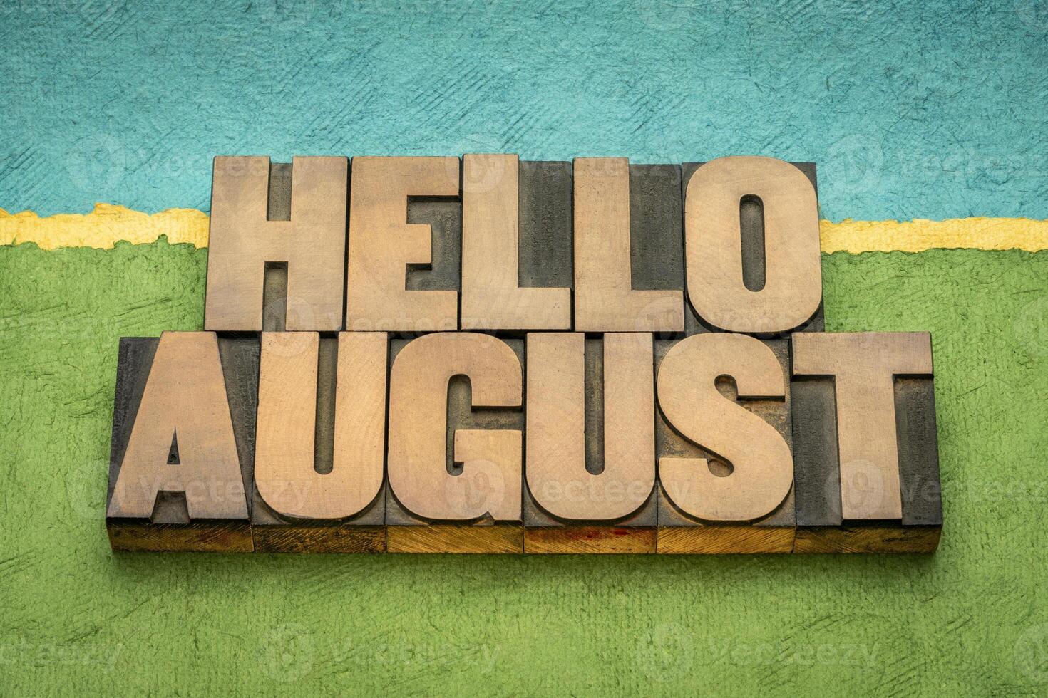 Hello August in vintage letterpress wood type against abstract paper landscape, calendar concept photo