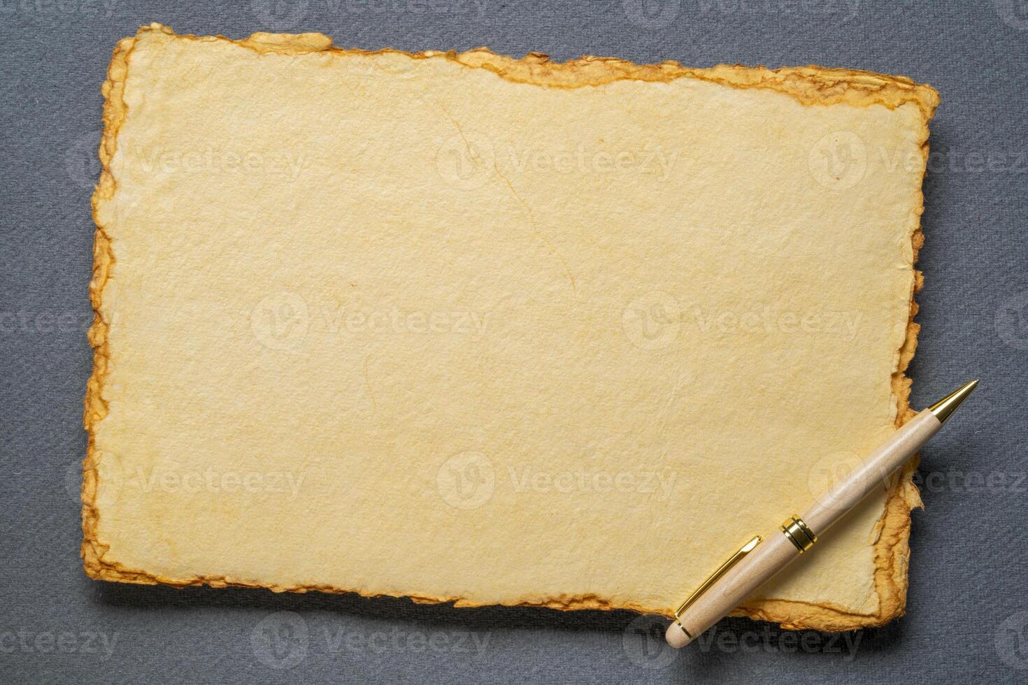 stack of tan toned heavyweight deckle edge paper sheets with a stylish pen photo