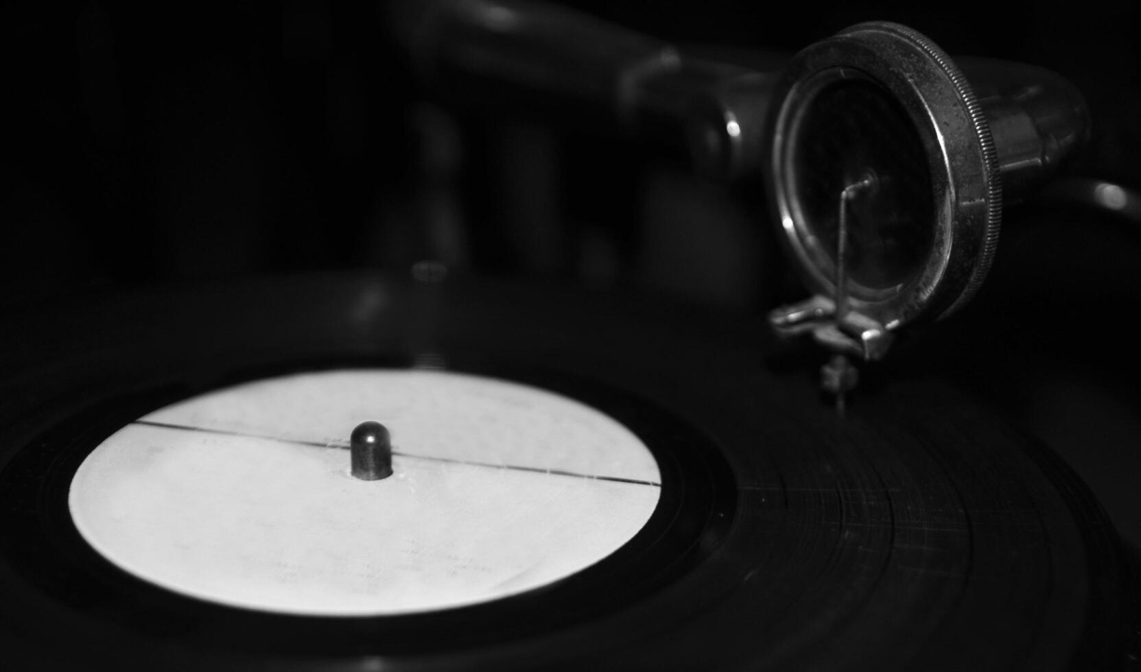 Black vinyl disc on a gramophone background. Black and white monochrome grayscale photo background.