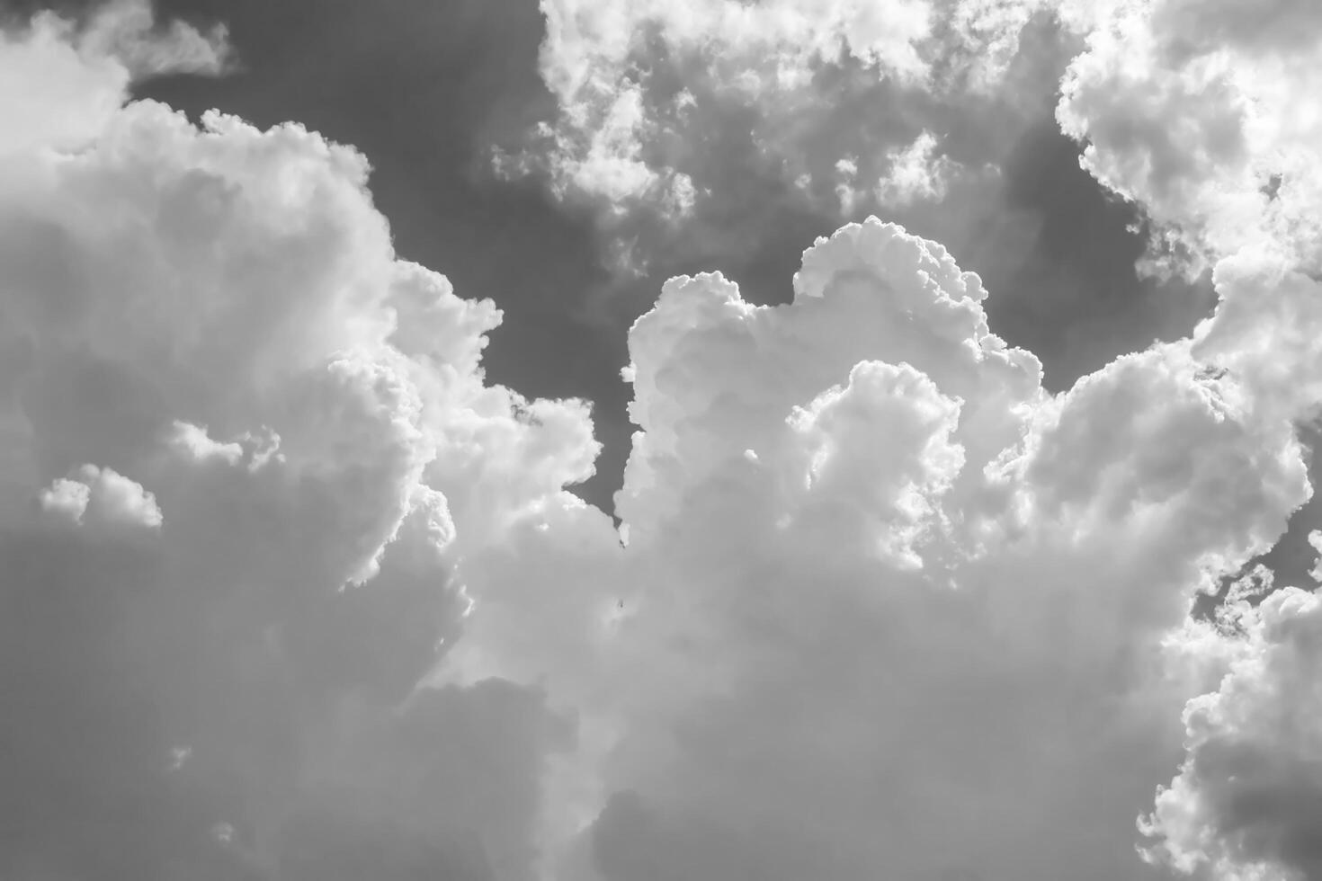 White clouds over blue sky. Black and white monochrome grayscale photo background.