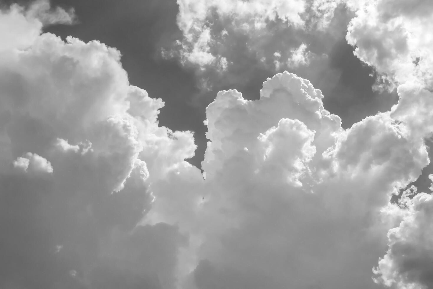 White clouds over blue sky. Black and white monochrome grayscale photo background.