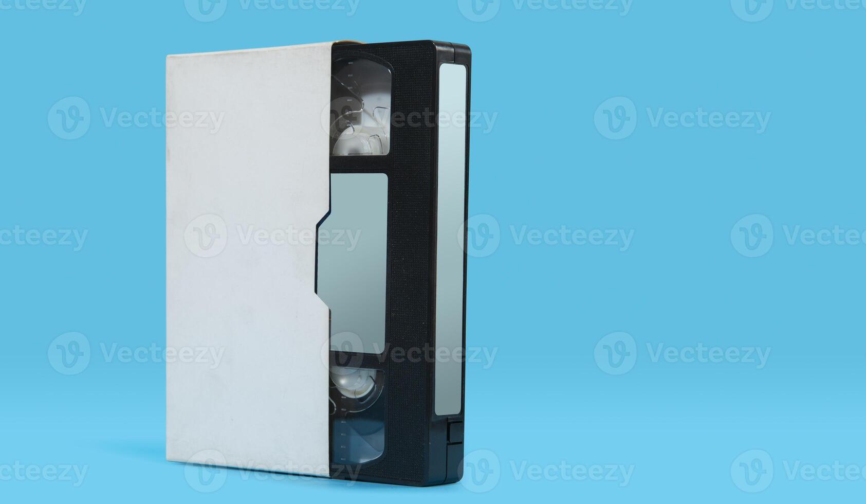 old black plastic VHS cassette with white case on a blue surface against blue background photo