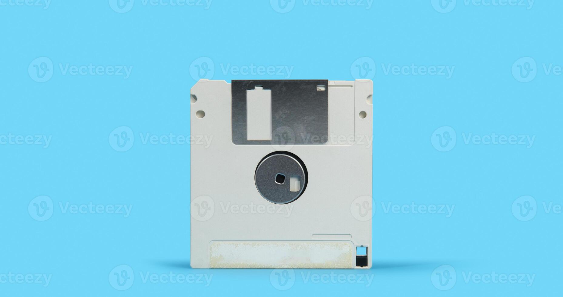 old white plastic square computer floppy disk on a blue surface against blue background photo