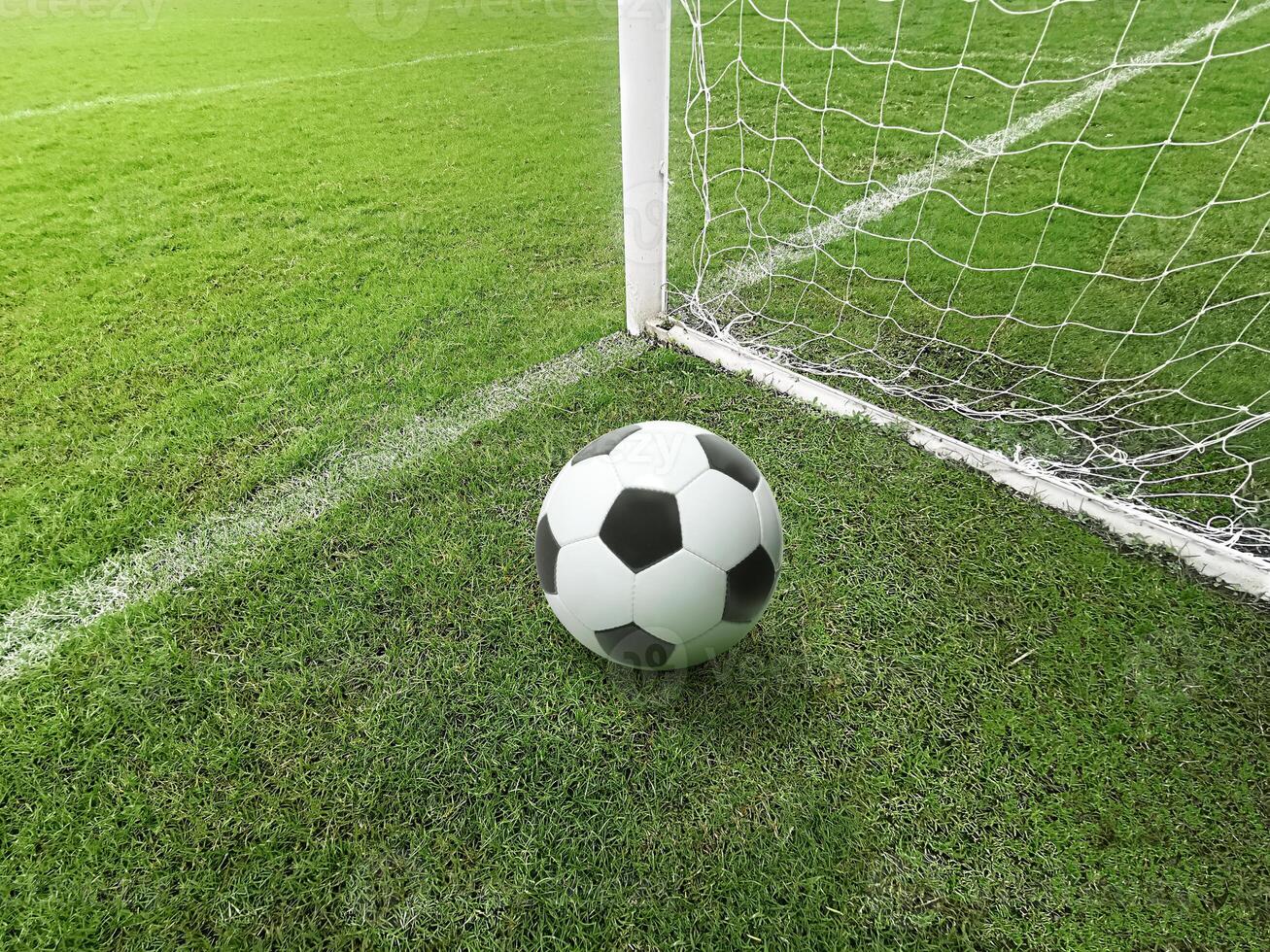 A soccer ball lies on a soccer field with green grass in a goal net after a goal scored by an athlete photo