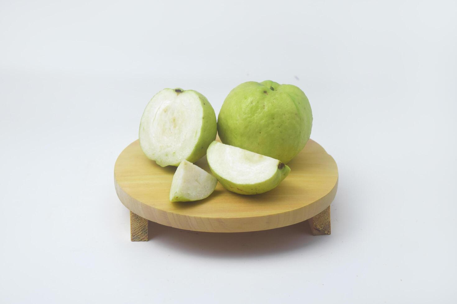 Photo of green guavas in a fruit basket and some have been cut off