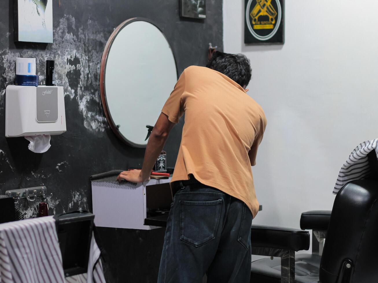 Atmosphere in barbershop, people, barber chair, mirror and various equipment on July 9, 2024 - Mataram, Indonesia photo