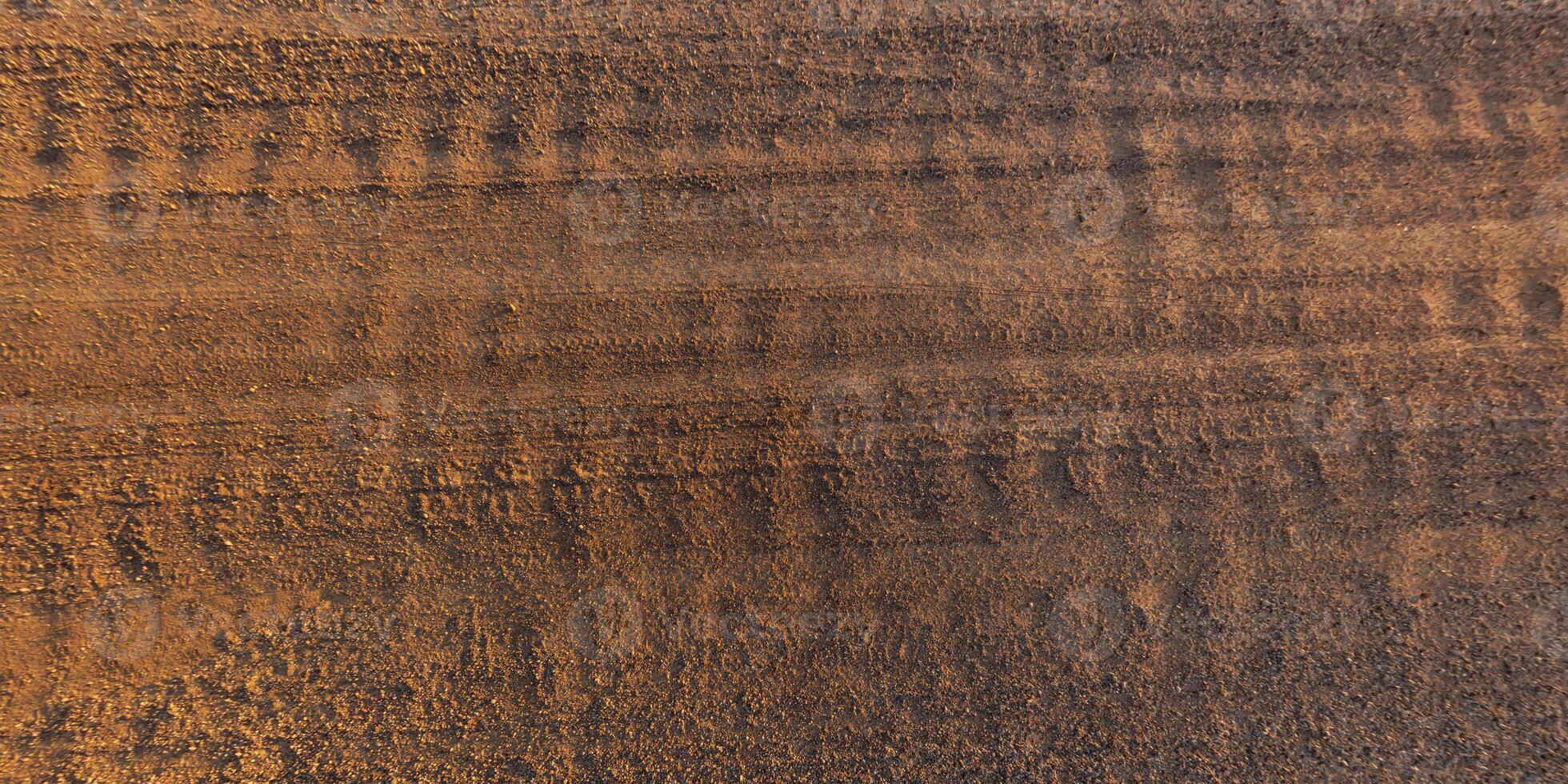 view from above on texture of dry muddy road with tractor tire tracks in countryside photo