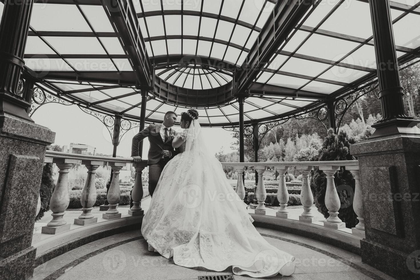 A bride and groom are kissing in front of a gazebo. Scene is romantic and intimate photo