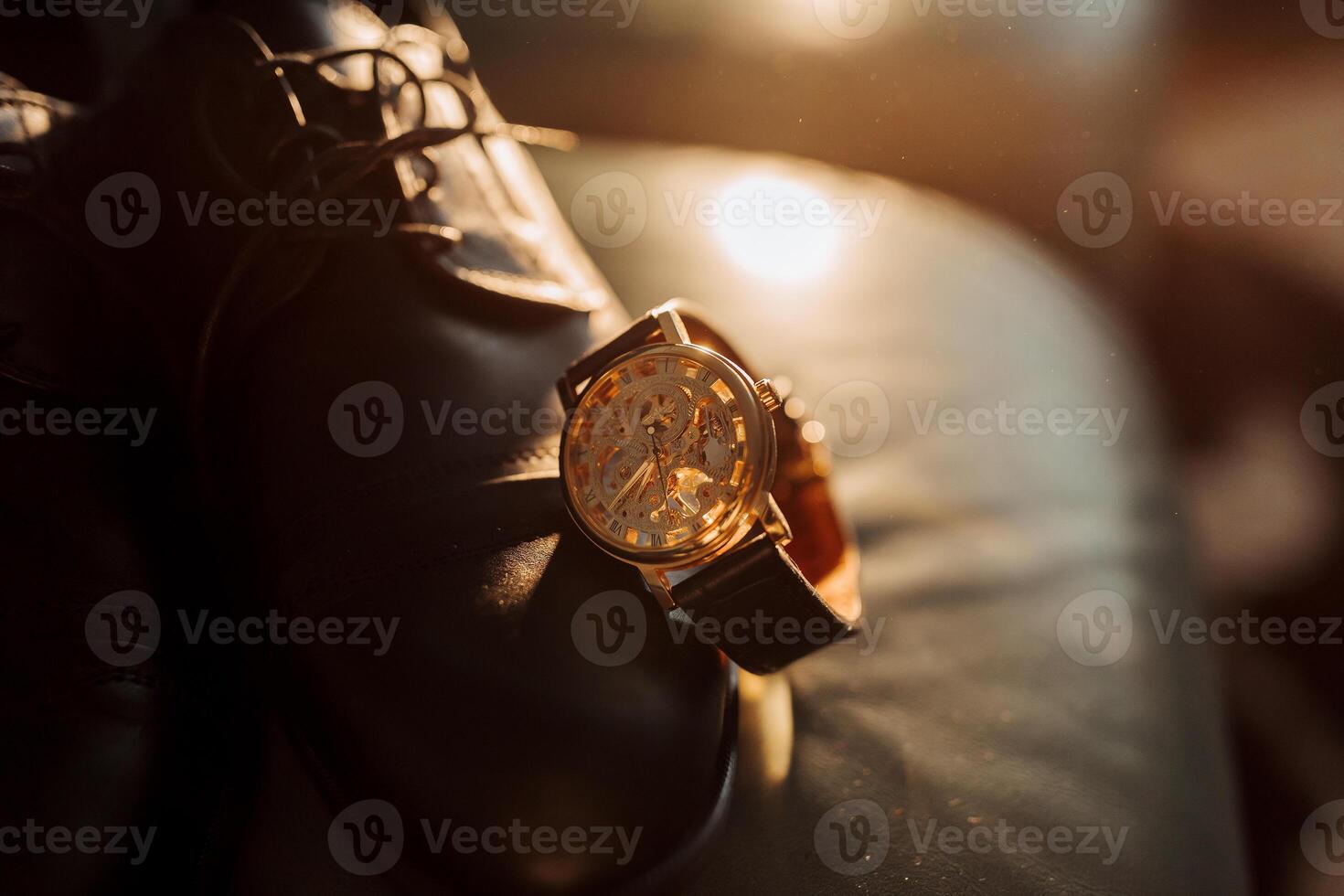 A watch is on a shoe. The watch is gold and has a black band photo