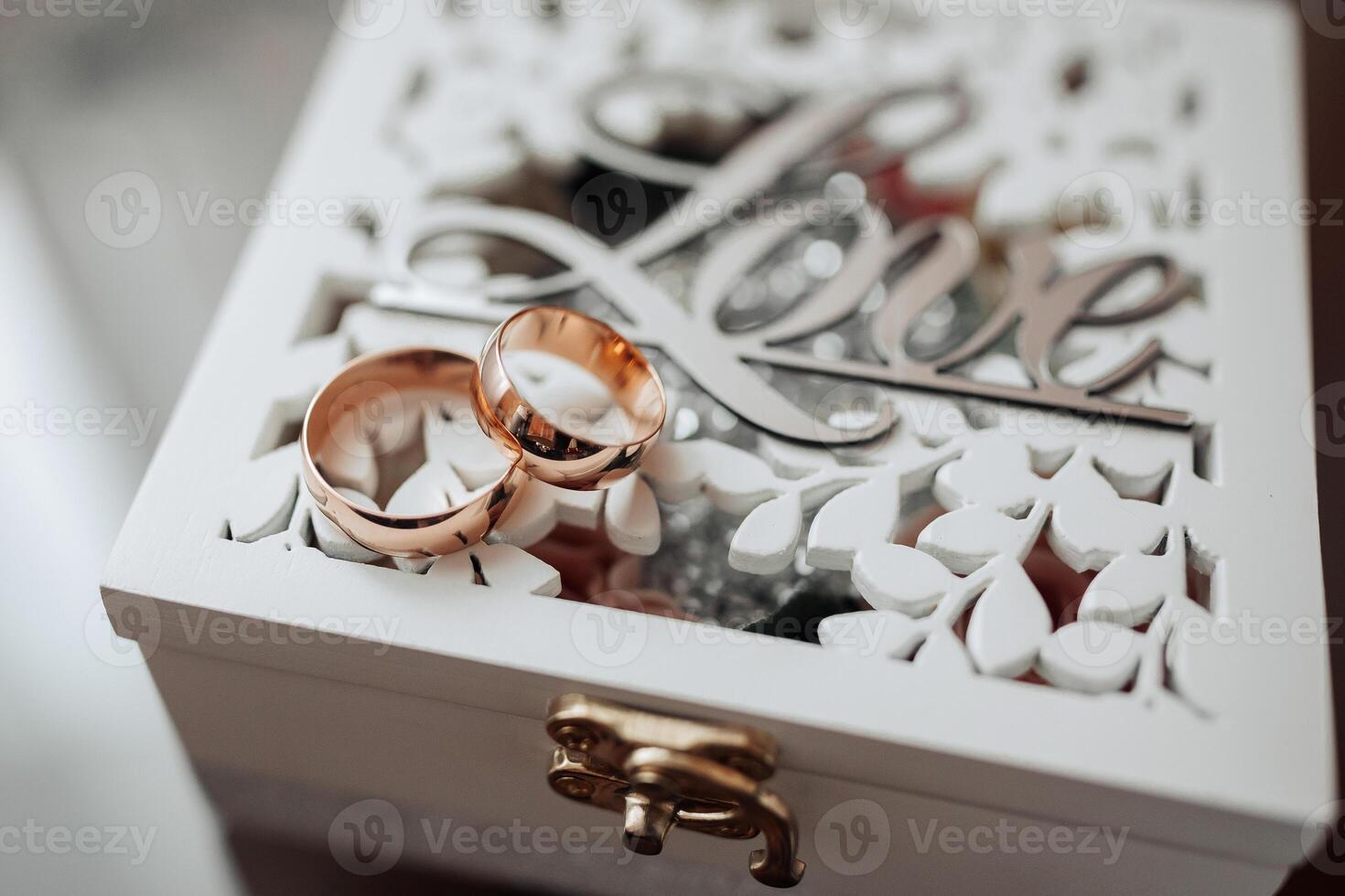 A white box with a heart on it and two gold wedding rings inside photo