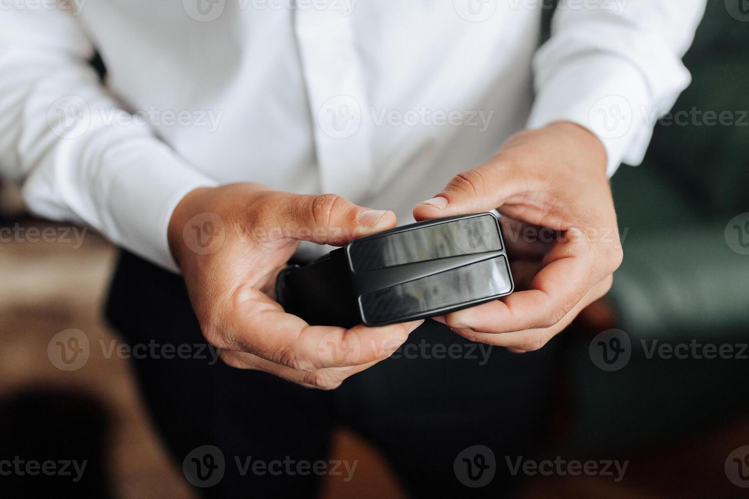 A man is holding a wallet in his hand. The wallet is black and has a silver zipper photo