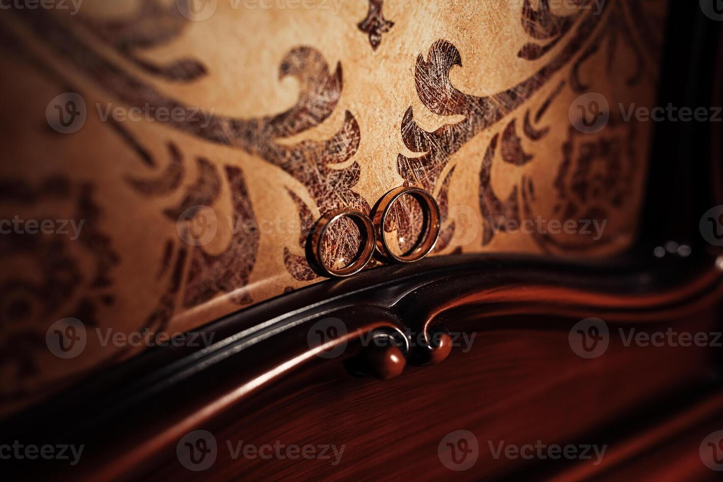 Two gold wedding rings are displayed on a wooden surface. The rings are placed next to each other, and the setting appears to be a vintage or antique piece. Concept of romance and love photo