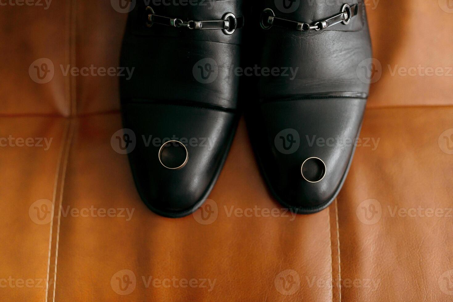 A pair of black shoes with a ring on the left foot and a ring on the right foot photo
