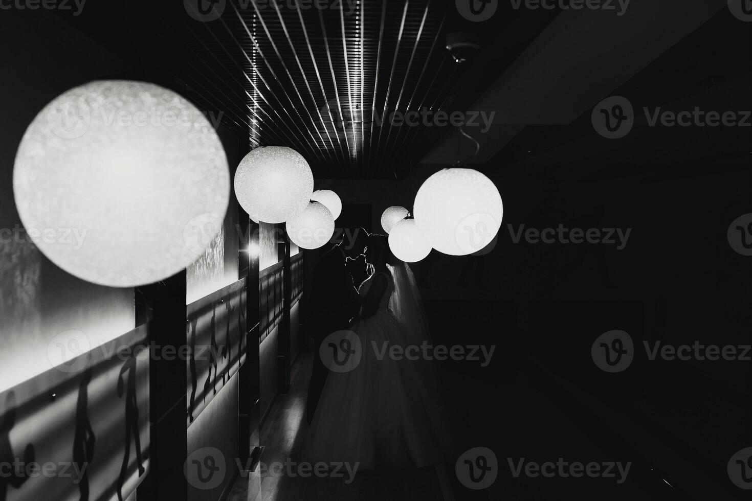 A couple is posing for a picture in a dark room with white lights. Scene is romantic and intimate photo