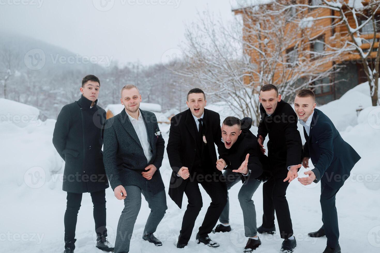 A group of men posing for a picture in the snow. They are all dressed in suits and ties photo