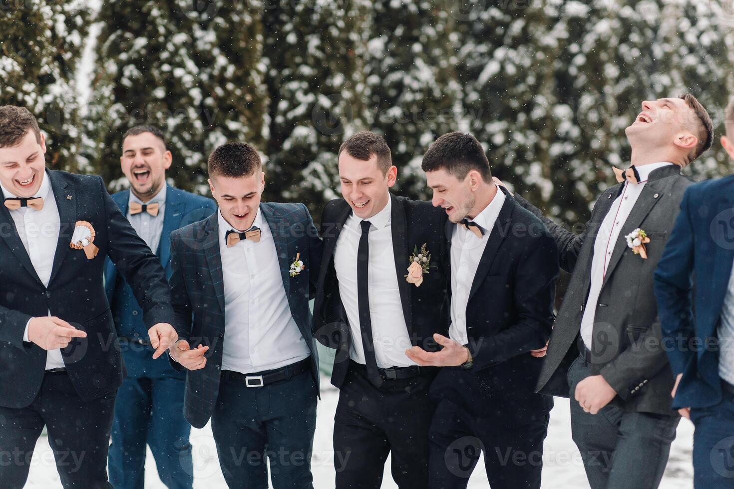 A group of men in suits are posing for a picture in the snow. They are all smiling and seem to be enjoying themselves photo