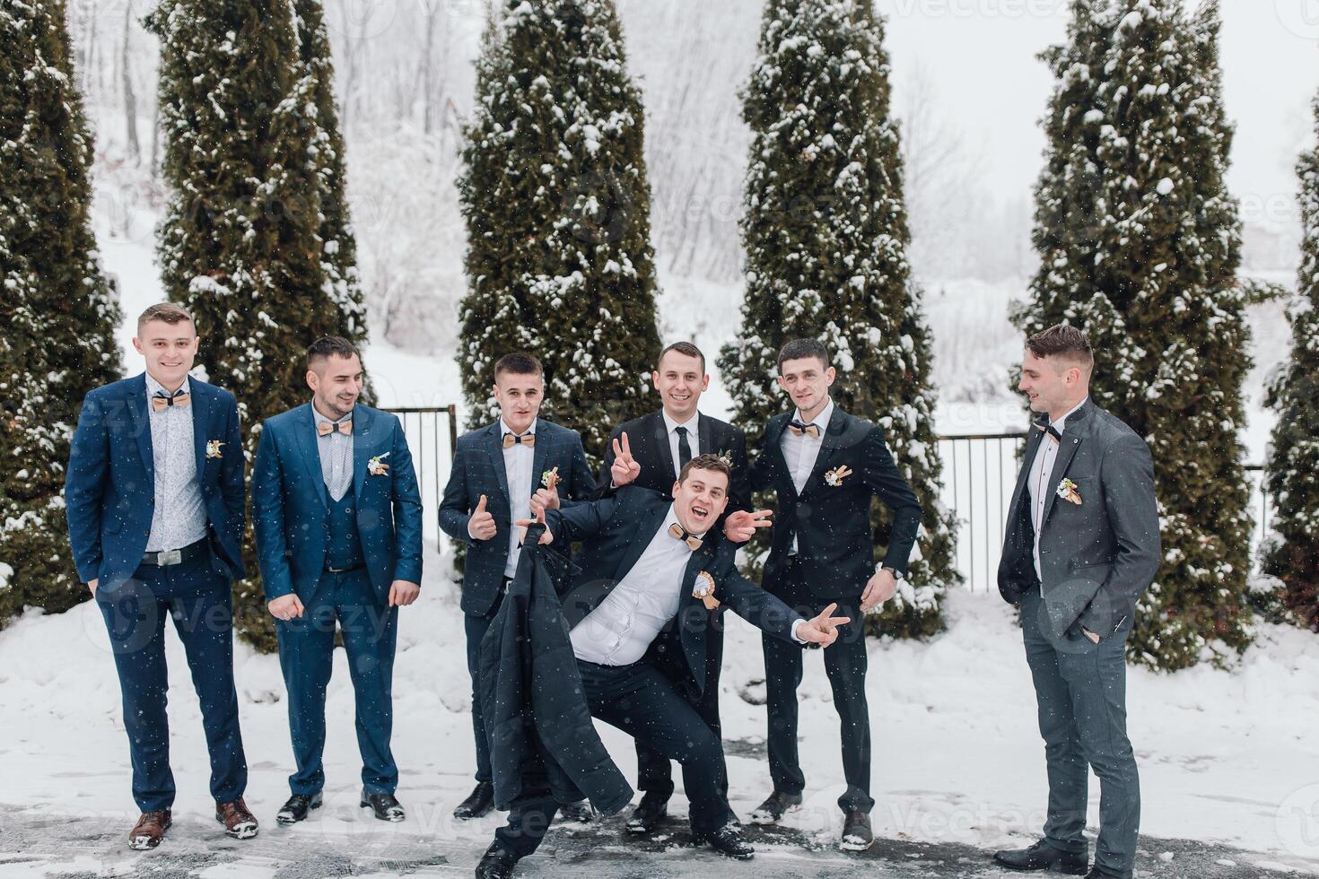 A group of men in suits are posing for a picture in the snow. They are all smiling and seem to be enjoying themselves photo
