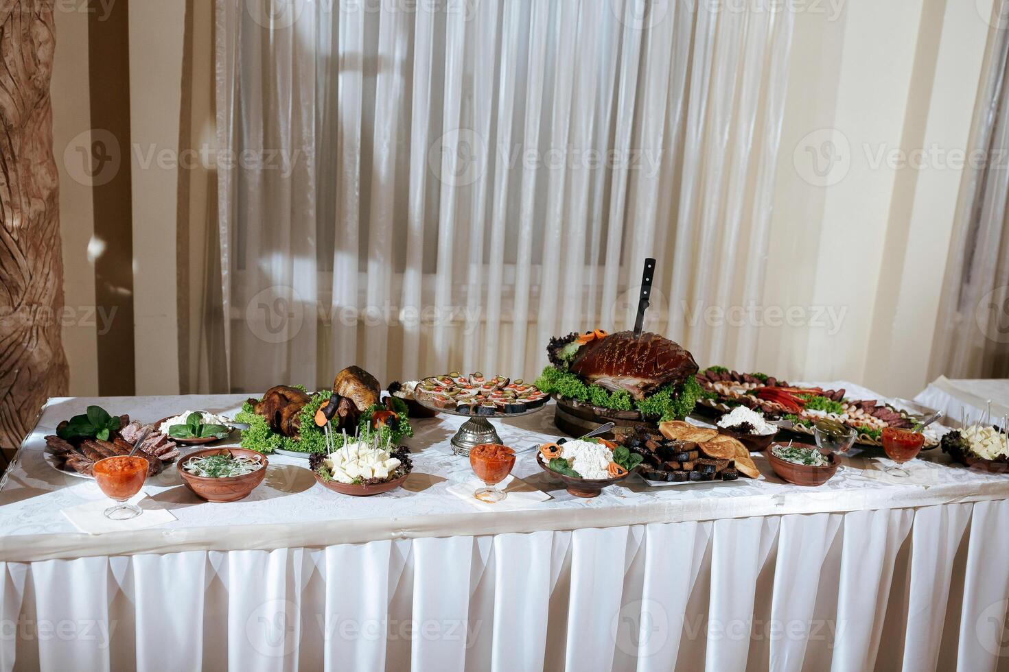 A table is covered with a variety of food, including a large salad. The table is set for a meal, and the food is arranged in bowls and on plates. The atmosphere is inviting and welcoming photo