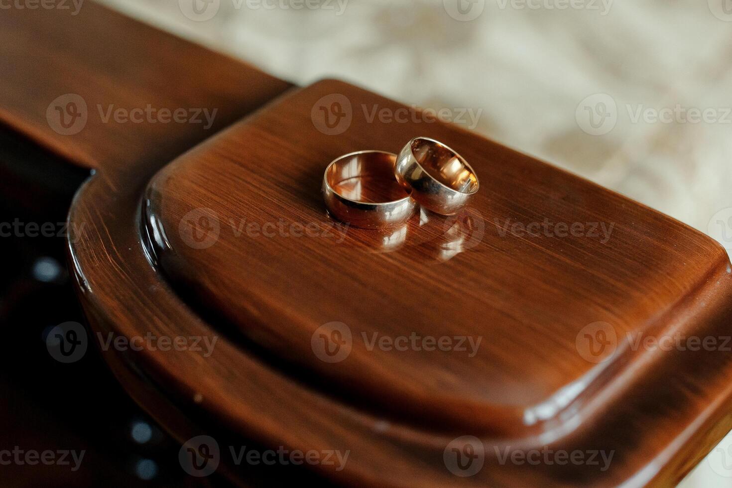 Two gold wedding rings are on a wooden surface. The rings are placed on top of each other, and the setting appears to be a wooden table. Concept of love and commitment photo