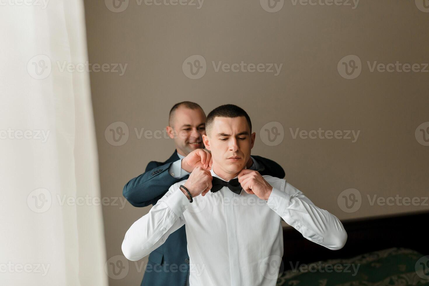 A man is getting his tie tied by another man photo