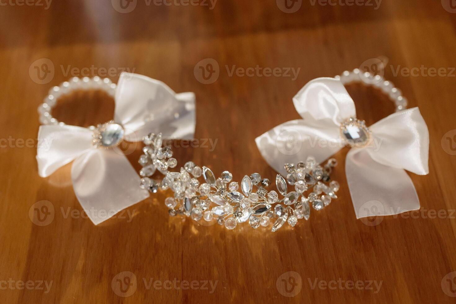 A pair of white bows are displayed on a wooden table. The bows are made of silver and are adorned with crystals. Concept of elegance and sophistication photo