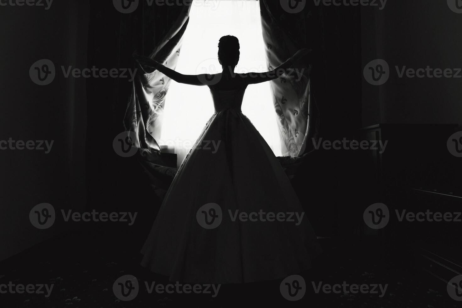 A woman in a wedding dress is standing in front of a window. Scene is elegant and romantic photo