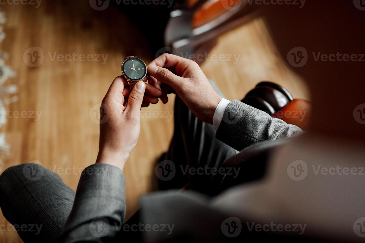 A man is holding a watch in his hand. He is wearing a suit and tie. The watch is black and silver photo
