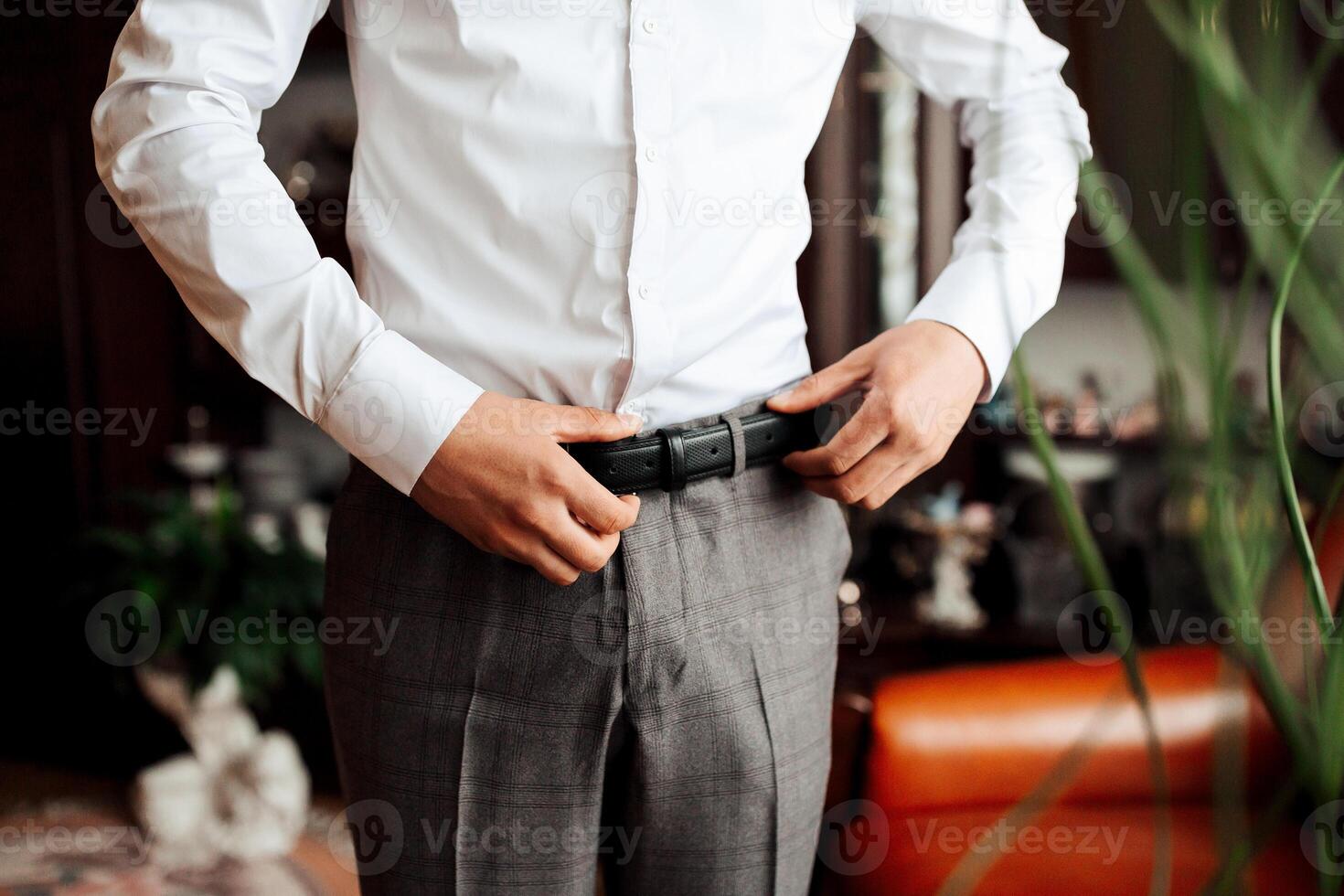 A man in a white shirt is adjusting his belt photo