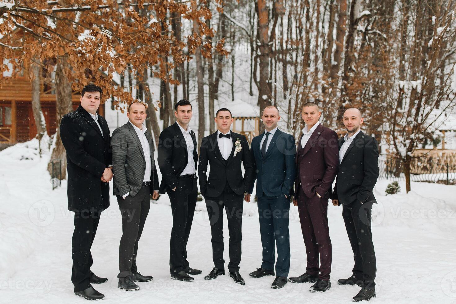 A group of men in suits are posing for a photo in the snow. Scene is formal and elegant, as the men are dressed in suits and ties. The setting of the photo is a snowy landscape