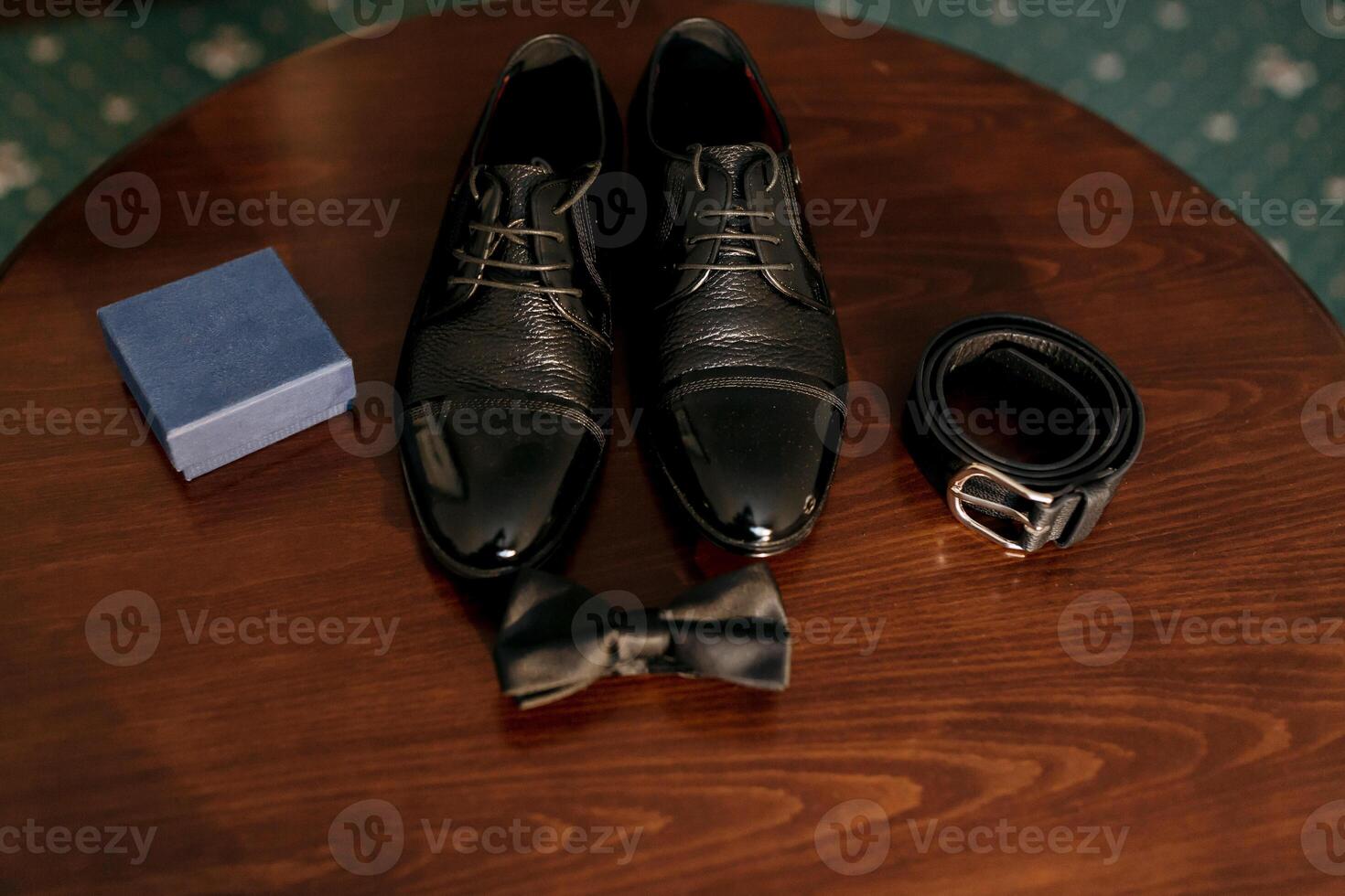 A pair of black shoes and a bow tie are displayed on a wooden table photo
