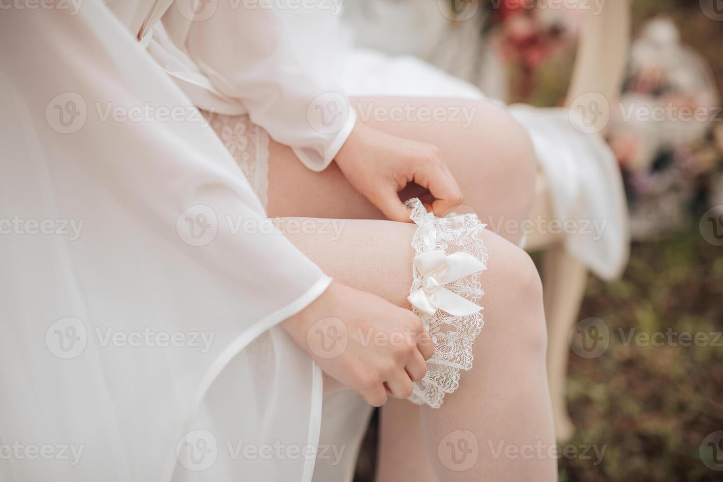 A woman in a white gown is sitting on a chair and adjusting her stockings. The scene is intimate and romantic, with the woman's focus on her appearance photo